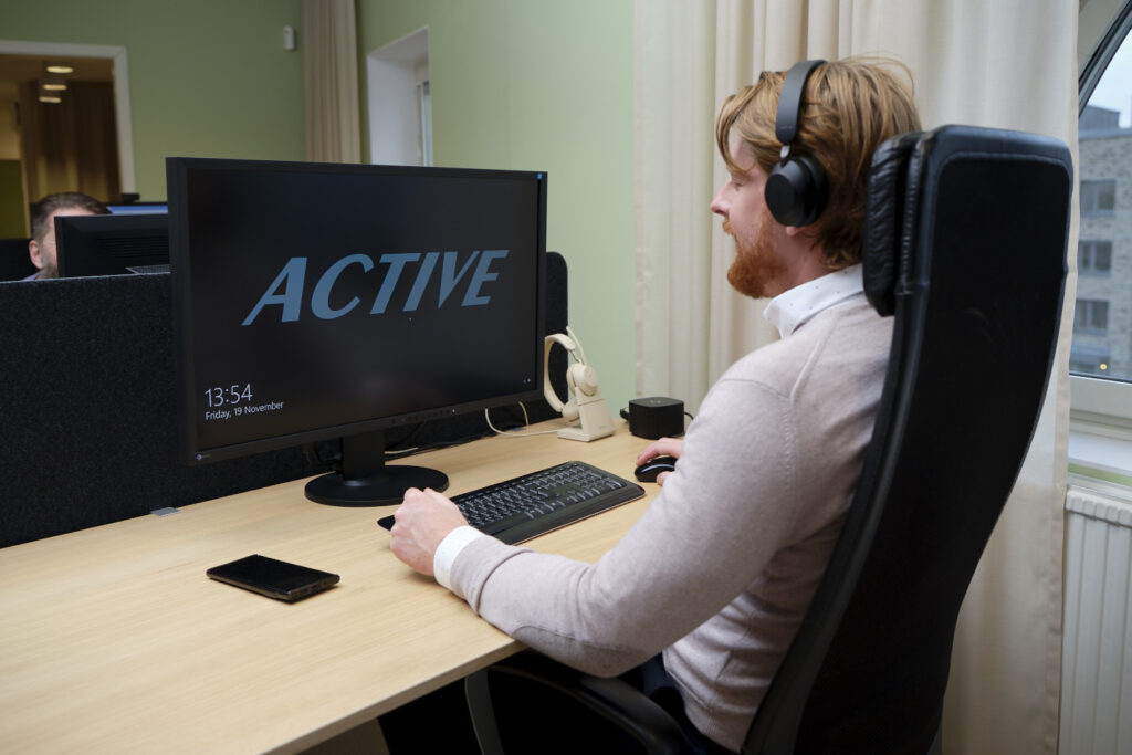 Medarbetare på Active IT arbetar med headset vid en arbetsplats med Active-skärm