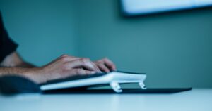 Hand på datormus vid en arbetsplats med skärm – Windows 10 efter supportstoppet